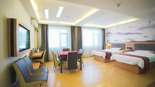 Quarto de hotel com área de refeições, duas camas, televisão e um mural na parede.