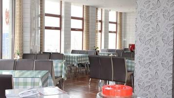 A restaurant with multiple tables and chairs, large windows, and a patterned wall.