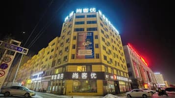 A multi-story hotel with illuminated signage, a ground-level entrance, and a visible parking area.