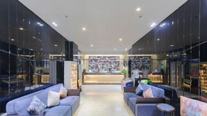 A modern lobby with a central reception desk, seating areas with sofas and armchairs, and a glass wall on one side. - PRETTY BANK HOTEL (Taiyuan)