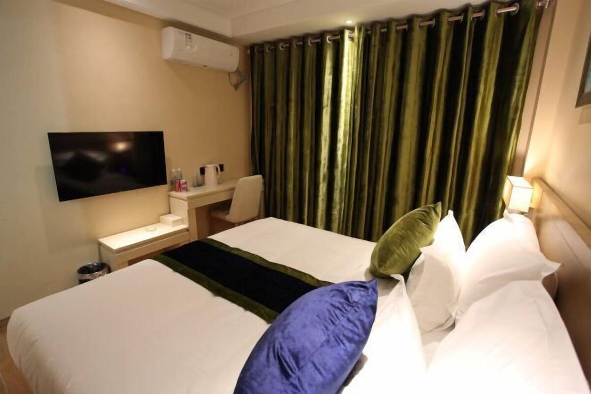 A hotel room with a bed, a desk, a television, and curtains.