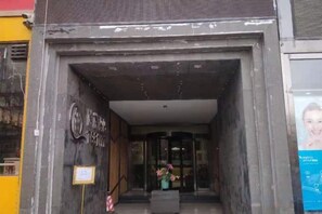 Ein Hotel Eingang mit dunkler Fassade, einem sichtbaren Schild und einem gerahmten Bild an der Wand.