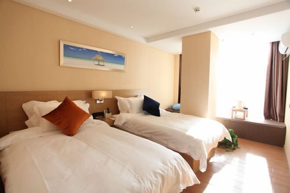 Quarto de hotel com duas camas, um quadro na parede e uma janela com cortinas.
