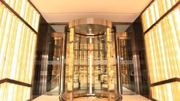 A modern elevator with glass panels and metallic accents, surrounded by walls with vertical wooden slats. - PRETTY BANK HOTEL (Taiyuan)