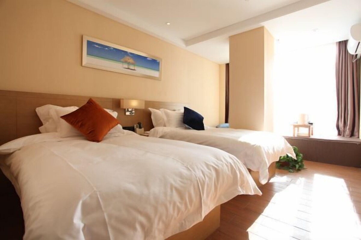 Quarto de hotel com duas camas, um quadro na parede e uma janela com cortinas.