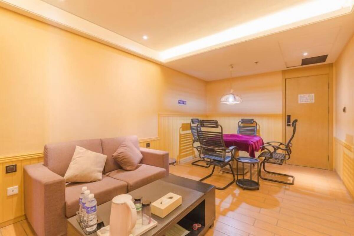 A hotel room with a sofa, a coffee table, a desk, and a chair with a table.