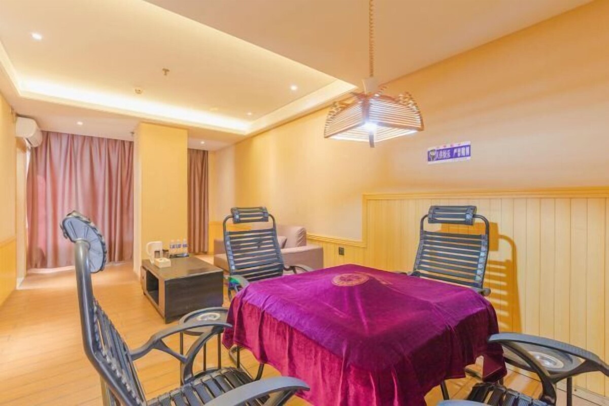 Quarto de hotel com uma mesa de jantar, cadeiras, um pequeno sofá, uma mesa de centro e um ventilador de teto.