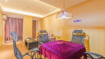 A hotel room with a dining table, chairs, a small sofa, a coffee table, and a ceiling fan.