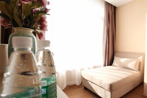 A hotel room with a bed, a vase with flowers, and two bottles of water. - PRETTY BANK HOTEL (Taiyuan)