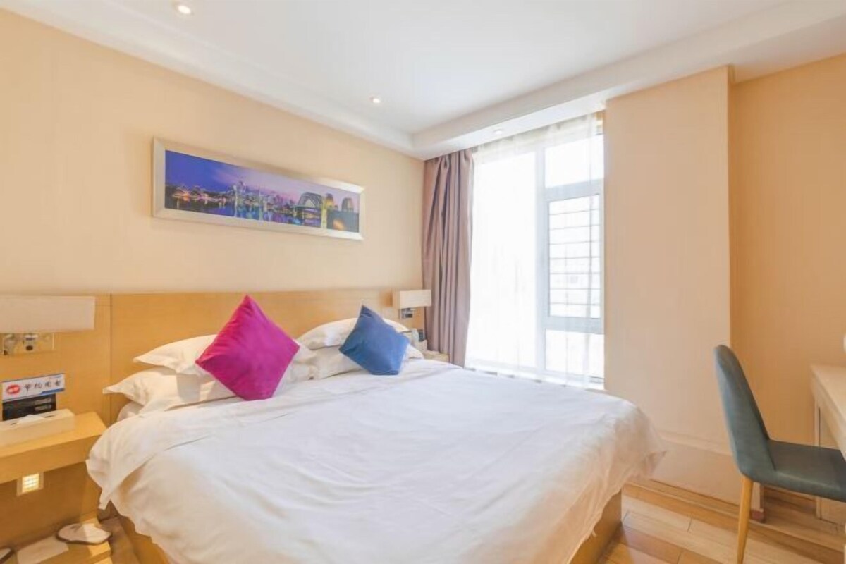 Quarto de hotel com cama, escrivaninha e cadeira.