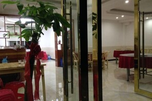 Comedor con mesas, sillas, una planta y un separador de vidrio.