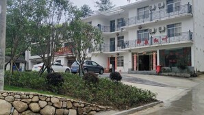 Un edificio de varios pisos con balcones, un muro de piedra y automóviles estacionados.