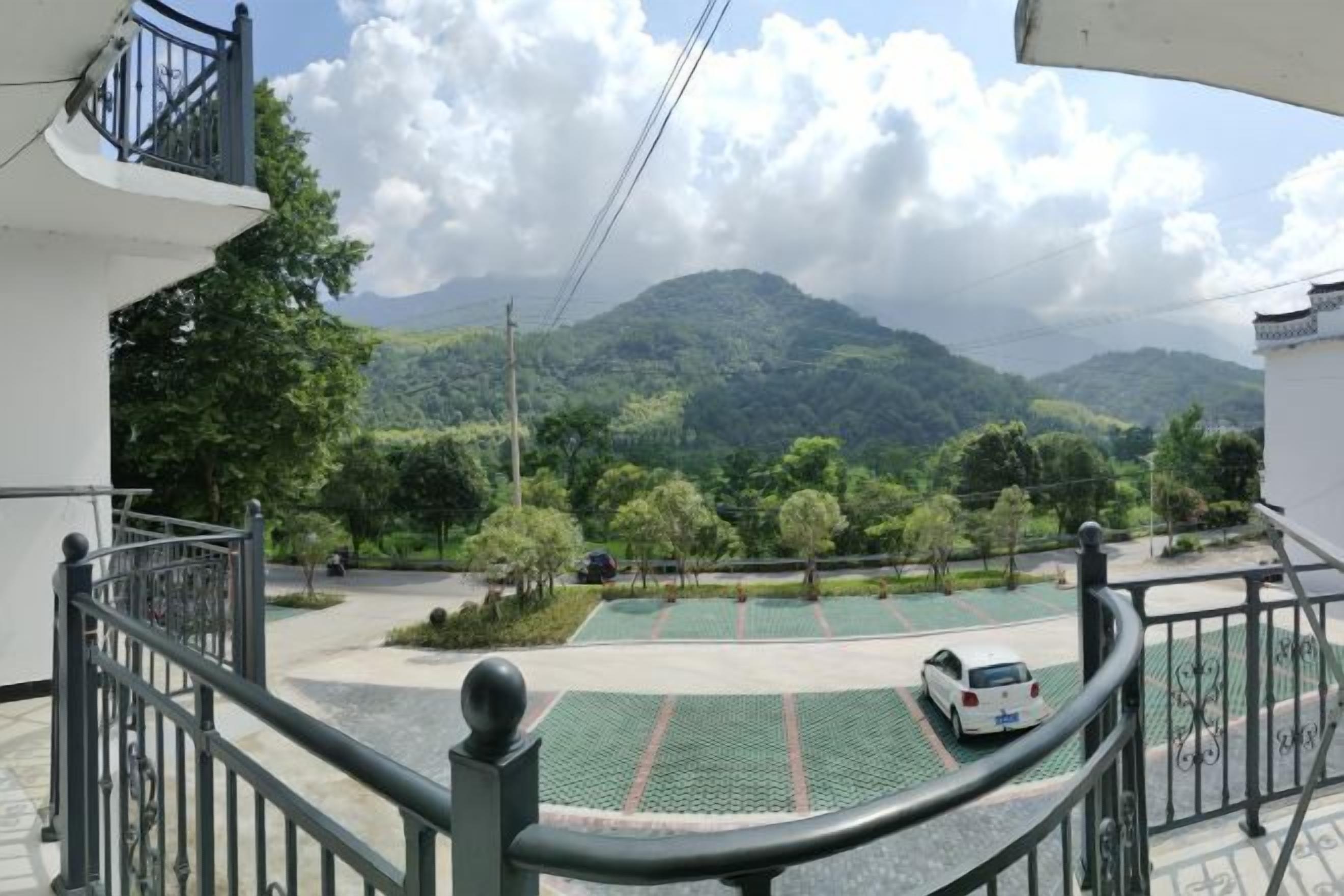 A residential area with a balcony overlooking a green landscape and mountains.