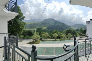 Zona residencial con balcón que da a un paisaje verde y montañas.