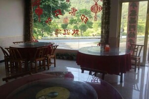 Interior de un restaurante con mesas y sillas redondas, un separador de vidrio y vista al exterior.