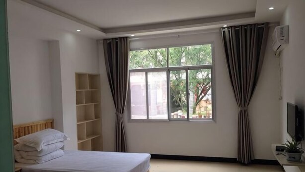 Un dormitorio con dos camas, una ventana, un televisor y una estantería.