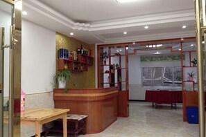 A reception area with a wooden counter, a table, and a window with a view. - Luotian Impression Hongye Mountain Villa (Luotian County)