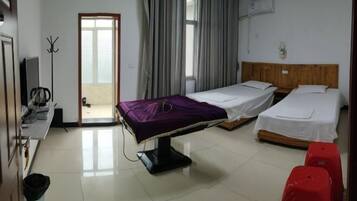 A hotel room with two beds, a TV, a coat rack, and a window with curtains.