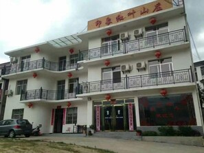 Ein mehrstöckiges Hotel mit Balkonen, Klimaanlagen und roten Laternen.