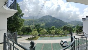 Un balcón con vista a un parque verde y una montaña al fondo.
