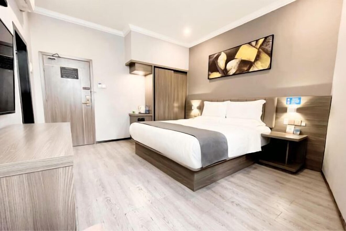 A hotel room with a bed, bedside table, and a wall-mounted TV.