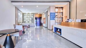 Una moderna hall d'albergo con reception, area salotto e parete con motivi geometrici.