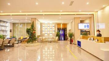 A hotel reception area with a reception desk, seating area, and a Christmas tree.