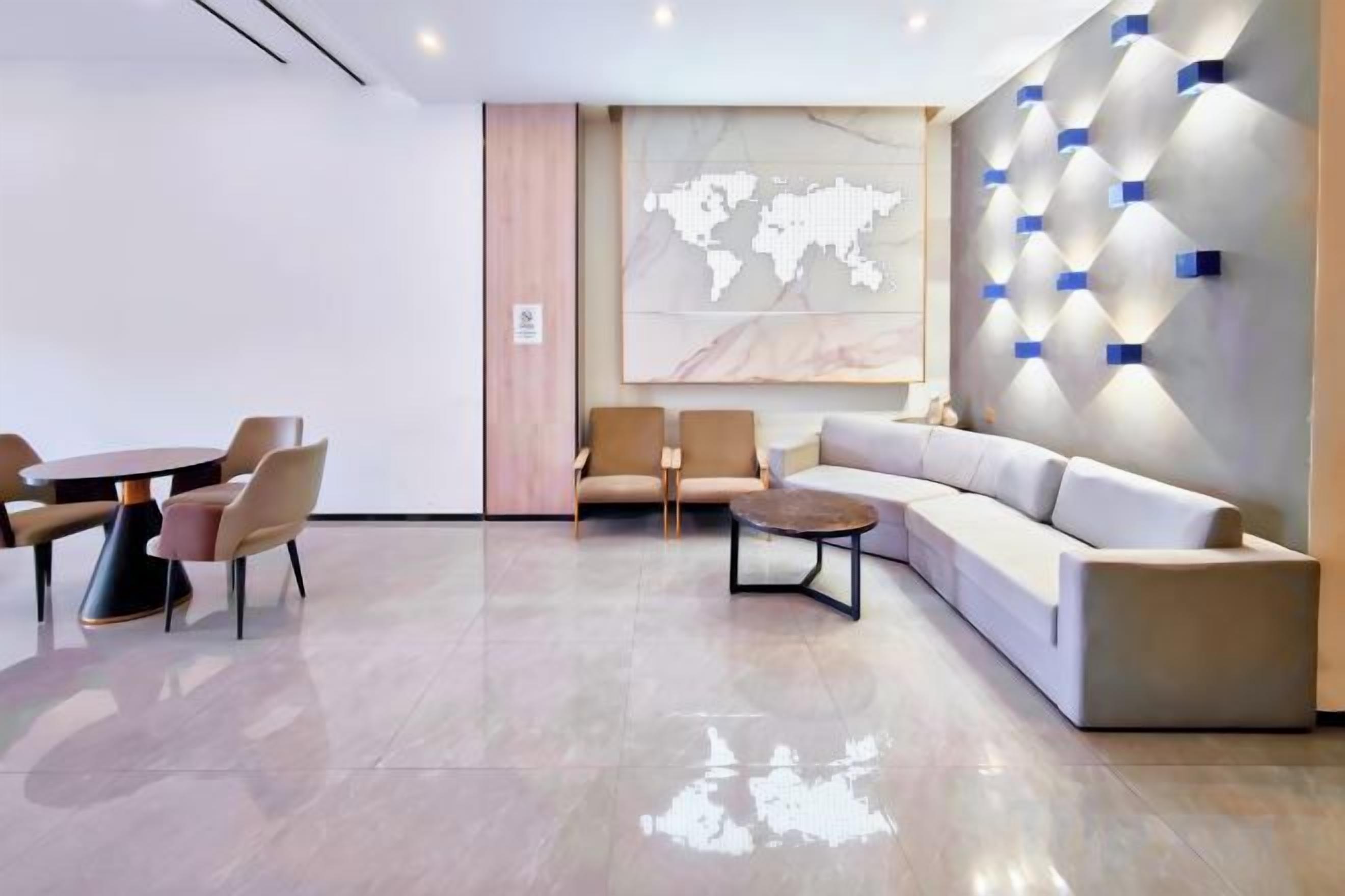 A modern lounge area with a round table, sofas, and a world map on the wall.