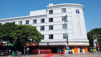 A white hotel with a prominent number '7' on the facade, a red carpet entrance, and a clear blue sky in the background.