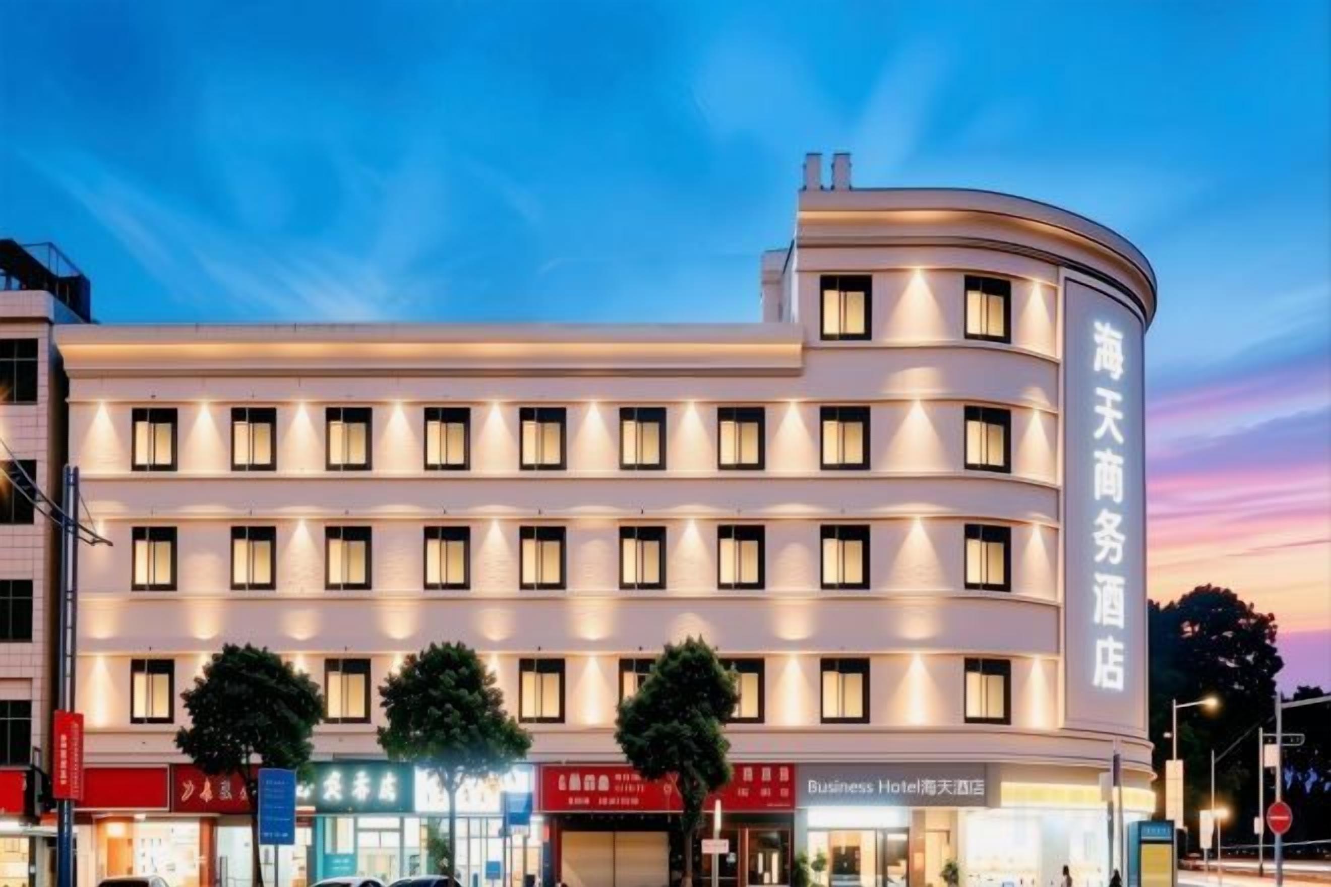 Een meerhoog hotel met een gebogen gevel, meerdere ramen en een bord dat het een zakenhotel aanduidt.