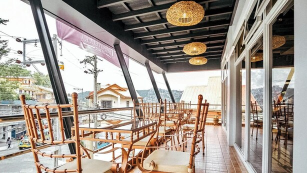 A restaurant with bamboo chairs and tables, large windows, and a view of the city.