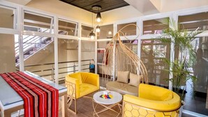 A modern interior with a yellow sofa, a hanging chair, and a table with a striped table runner.