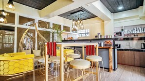 A modern kitchen with a central island, bar stools, and a hanging light fixture.