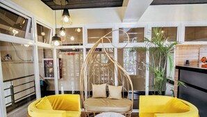A modern interior with a hanging chair, yellow sofas, and a round table with a book.
