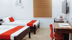 A hotel room with two beds, a desk, a chair, a TV, and a window with blinds. - Reddoorz @ David's Travellers Inn Cavite (General Trias)