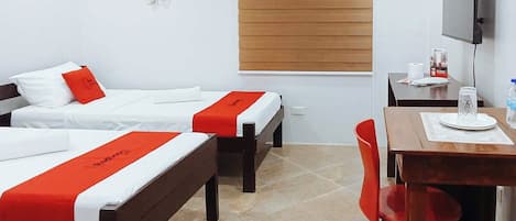 A hotel room with two beds, a desk, a chair, a TV, and a window with blinds.