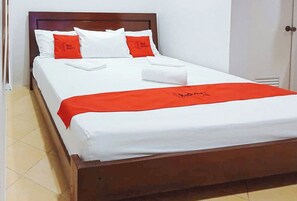 A neatly made bed with white and red bedding, a wooden headboard, and a red blanket with a logo. - Reddoorz @ David's Travellers Inn Cavite (General Trias)