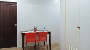 A small room with a wooden door, a white wall, and a table with two red chairs. There are water bottles on the table. - Reddoorz @ David's Travellers Inn Cavite (General Trias)