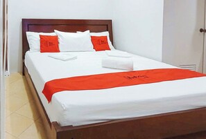 A neatly made bed with white and red bedding, a wooden headboard, and a red bed runner with text. - Reddoorz @ David's Travellers Inn Cavite (General Trias)