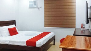 A hotel room with a bed, a wooden desk, a chair, a window with blinds, and a wall-mounted air conditioner. - Reddoorz @ David's Travellers Inn Cavite (General Trias)