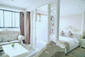 Une chambre d’hôtel avec une grande fenêtre, un canapé, un lit et une table blanche.