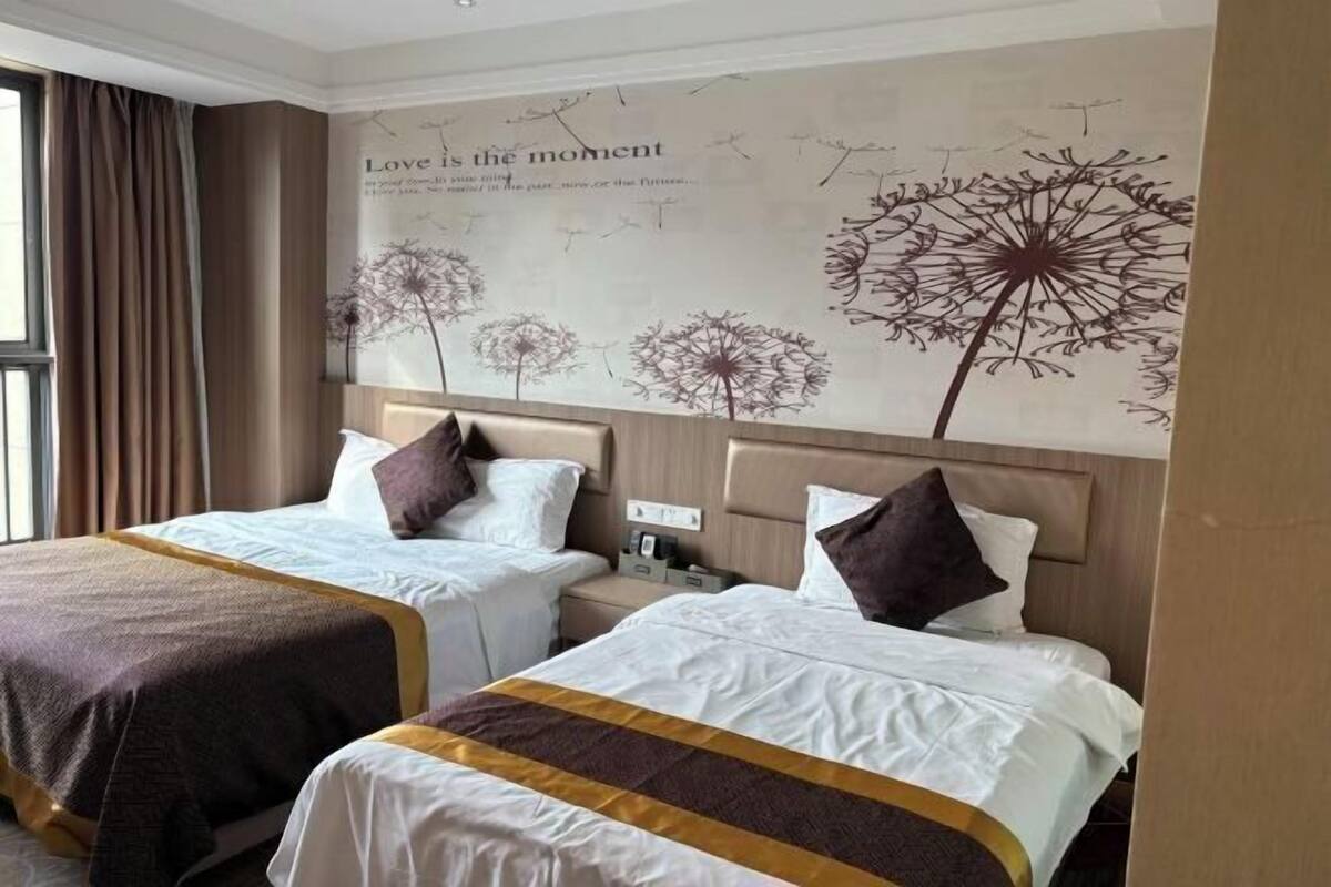 Une chambre d’hôtel avec deux lits, une fresque murale et une fenêtre avec des rideaux.