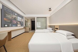 Habitació d'hotel amb un televisor LED gran, dos llits, un escriptori i una cadira.