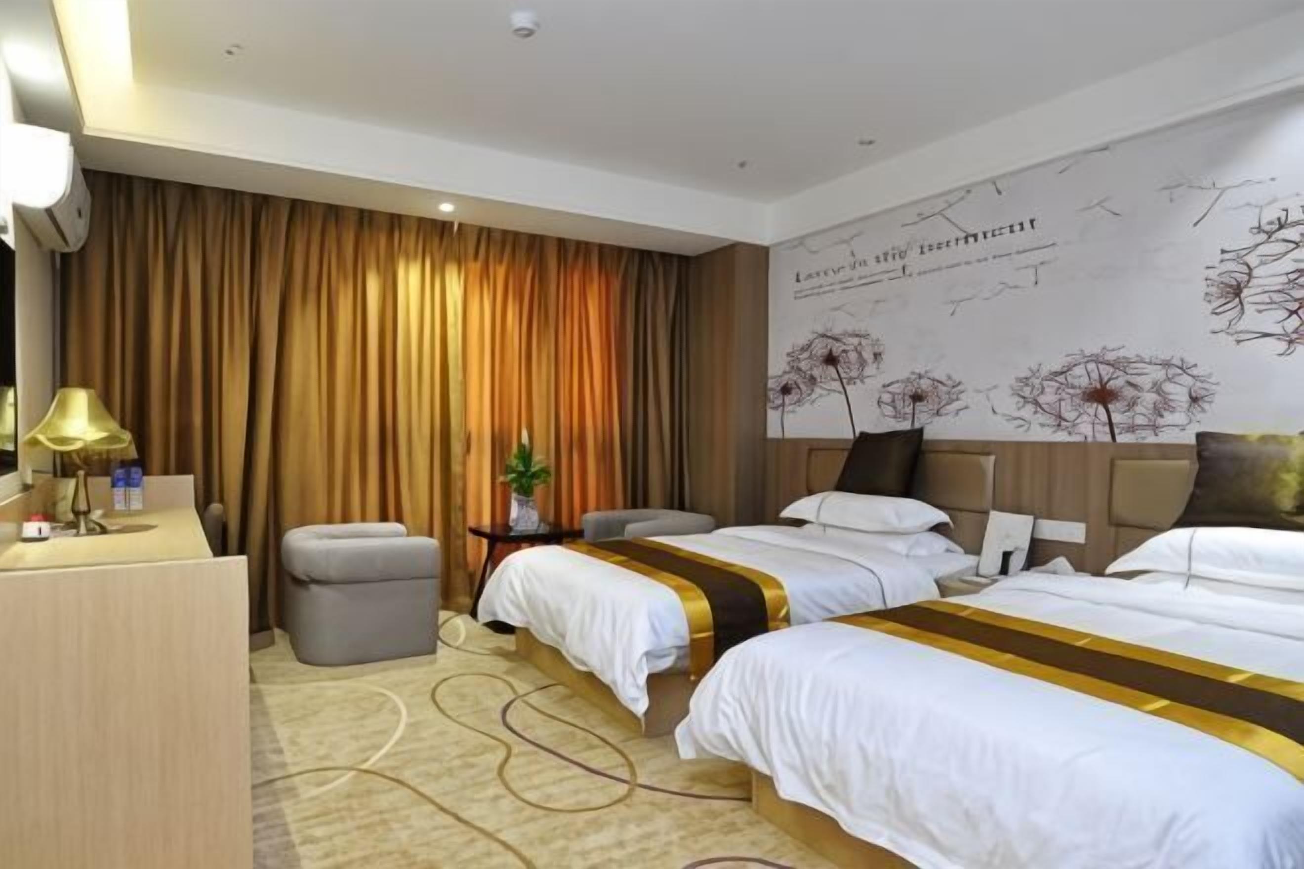 Ein Hotelzimmer mit zwei Betten, einem Schreibtisch, einem Stuhl, einem kleinen Tisch mit Lampe und einem großen Fenster mit Vorhängen.