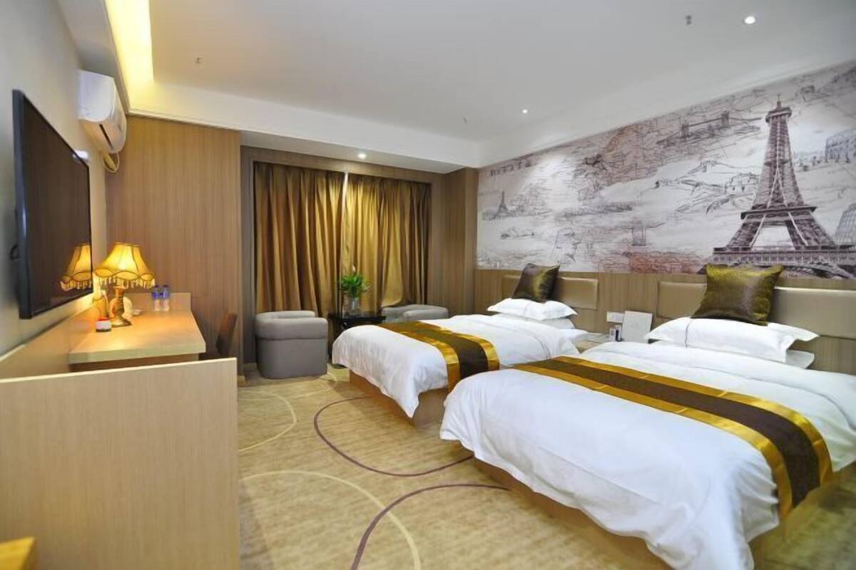 Une chambre d’hôtel avec deux lits, un bureau avec une lampe, un miroir et une fresque représentant la Tour Eiffel.