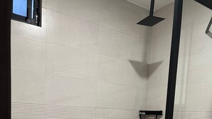 Un petit espace douche fermé, équipé de toilettes et d’une étagère.