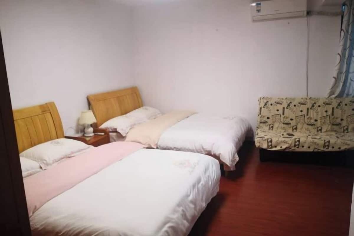 Une chambre d’hôtel avec deux lits, une tête de lit en bois, une table de chevet avec une lampe et un canapé à motifs.