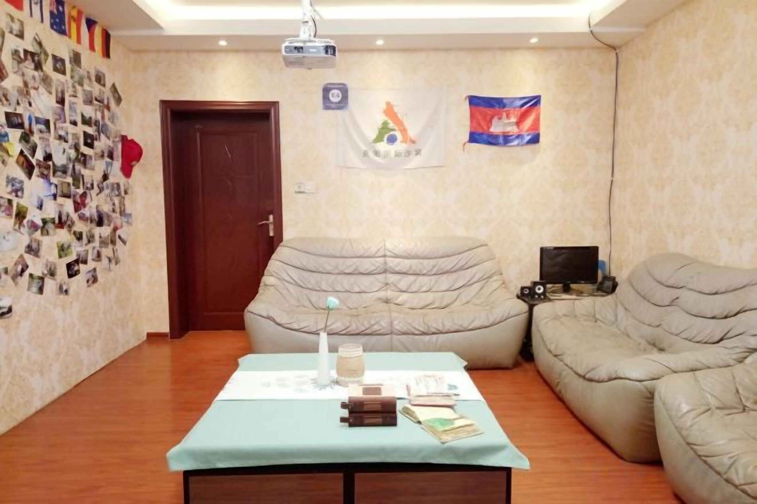 A room with a table, two couches, a projector, and flags on the wall.