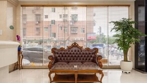 Una habitación con un ventanal grande, un sofá, una planta en maceta y un mostrador de recepción.