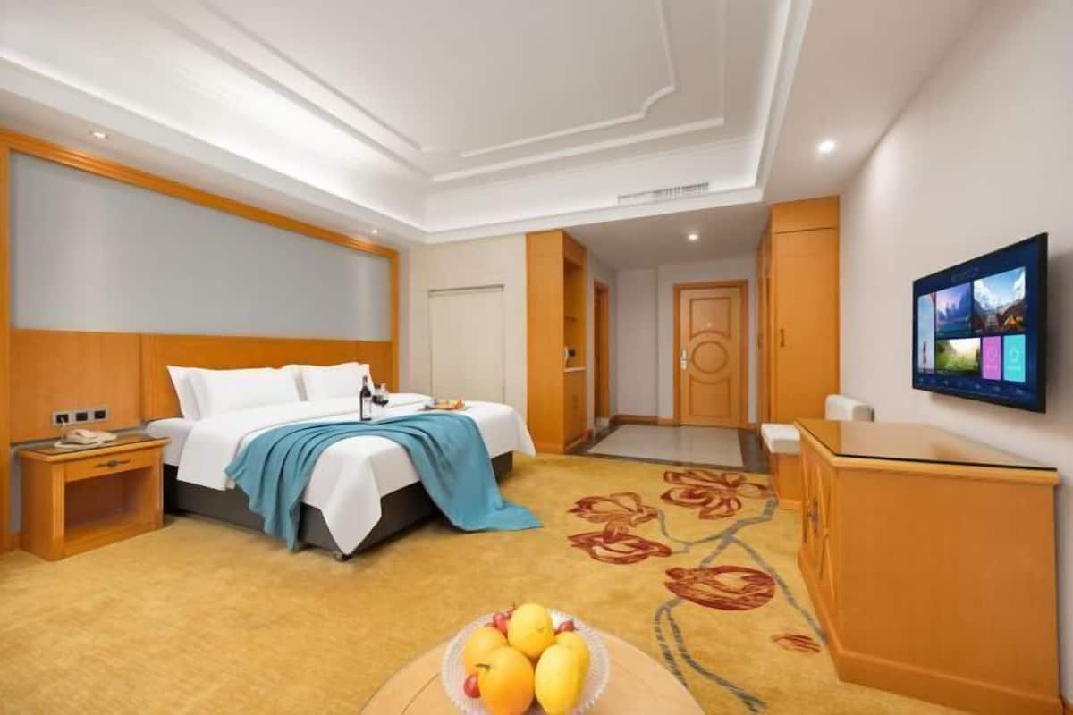 Ein Hotelzimmer mit Bett, Nachttisch, Fernseher und einer Obstschale.